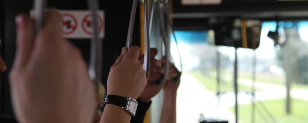 People holding the hand straps on a bus